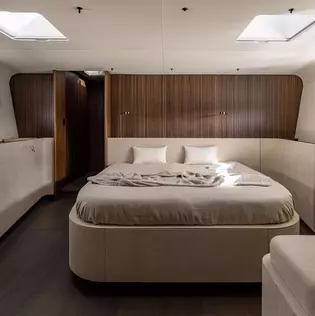 The photo shows the bedroom of the Y9 yacht with luxurious bed and noble wooden wall.