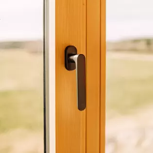 The illustration shows the AVUS window handle in a wood-style house.