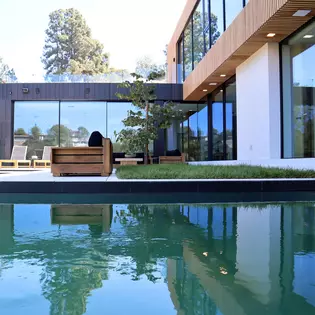 La foto muestra la casa privada en Beverly Hills con piscina y terraza en el jardín delantero. 