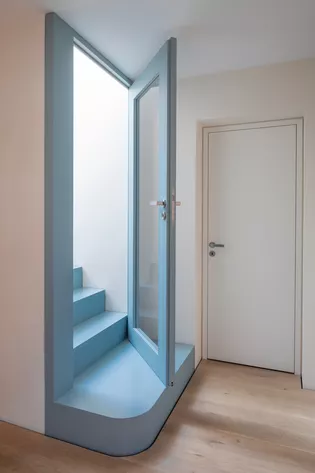 Die Treppe im Haus Soho ist nicht irgendeine funktionale Treppe. Sie wurde in mattes, helles Blau gekleidet. Die unterste Sockelstufe ist einladend und großflächig, ihre Ecke zum Gang hin weich gerundet.