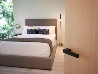 The picture shows the bedroom with a wooden door and door handle R8 ONE in graphite black.