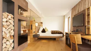 La imagen muestra un dormitorio en tonos naturales con un cuarto de baño abierto adyacente.