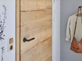 Das Bild zeigt ein Jugendzimmer mit Holztür und Griffwerk Türgriff Lucia mit smart2lock in der Oberflächenfarbe Graphitschwarz.