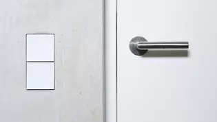 L'image montre un détail de la porte et des poignées de porte Lucia smart2lock dans la maison vv