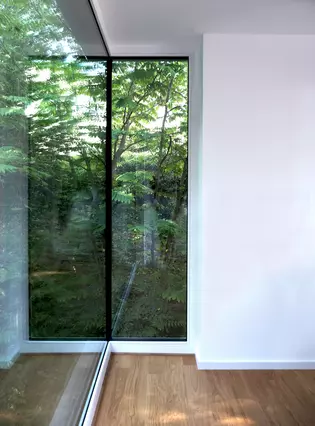 La ilustración muestra una ventana de esquina de la casa H con vistas a la Naturaleza.