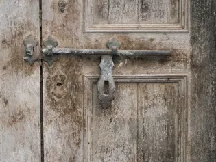 The illustration shows an old wooden door with a rustic metal latch.
