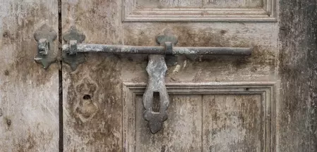 The illustration shows an old wooden door with a rustic metal latch.