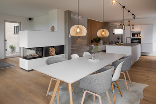 Pebble colored exposed concrete was used for walls and floor. The floor and an open wall of lined wooden beams are made of oak wood, which goes well with the velvety white of the kitchen.