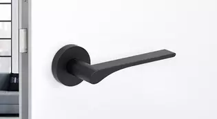 The picture shows the Griffwerk door handle LEAF LIGHT in graphite black in a living room.