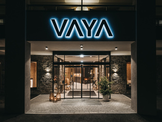 The picture shows the entrance of the hotel at night. Fully illuminated and with stone facade.
