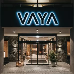 Die Abbildung zeigt den Eingang des Hotels bei Nacht. Voll beleuchtet und mit Steinfassade.