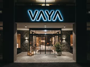 La imagen muestra la entrada del hotel por la noche. Totalmente iluminada y con fachada de piedra.