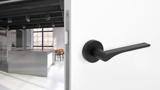 The picture shows the Griffwerk door handle LEAF LIGHT in graphite black in a living room.