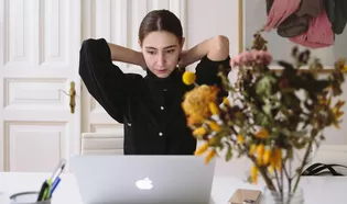 Die Abbildung zeigt eine Frau in einer Altbauwohnung vor ihrem Laptop.