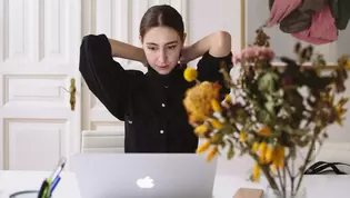 The image shows a woman in an old apartment in front of her laptop.