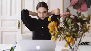 The image shows a woman in an old apartment in front of her laptop.