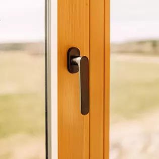 L'illustration montre la Poignée de fenêtre AVUS dans une maison de style bois.