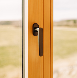 The illustration shows the AVUS window handle in a wood-style house.