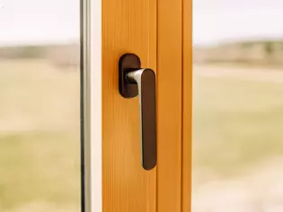 The illustration shows the AVUS window handle in a wood-style house.