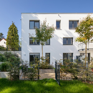 Die Abbildung zeigt den Wohnungsbau Lotthersgarten in Fürth von außen mit Vorgarten. 