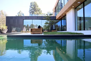 La foto muestra la casa privada en Beverly Hills con piscina y terraza en el jardín delantero. 