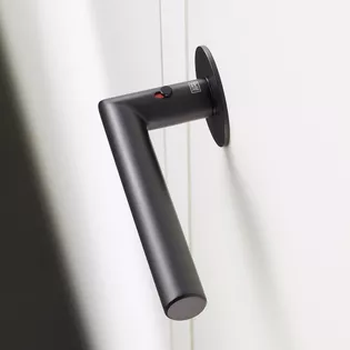 The picture shows the door handle Lucia in graphite black mounted on a white wooden door.
