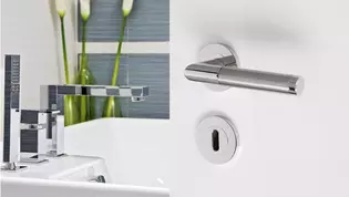 Living situation shows a bathroom with glossy furniture and the GRIFFWERK door handle set Loredana Professional