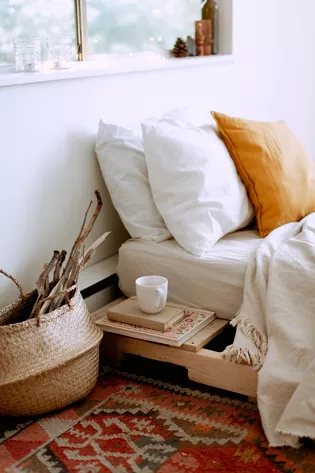 La foto muestra una cama en el dormitorio, amueblado en estilo etno.