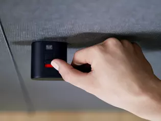 Griffwerk door handle Avus One samrt2lock in graphite black The picture shows the Griffwerk door handle Avus One samrt2lock in graphite black with a woman's hand on the handle from above. This closes straight the door handle with the help of the latch.