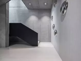 Couloir au rez-de-chaussée avec béton et accents noirs Couloir sobre au rez-de-chaussée avec béton apparent robuste et accents noirs modernes - un design minimaliste rencontre des matériaux puissants.