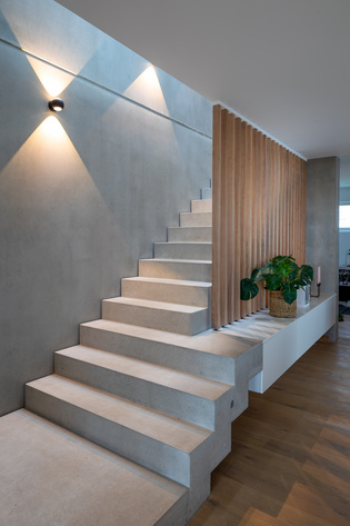 The staircase is spacious, wide and made of fine but heavy concrete. The open demarcation made of wooden beams does not create any narrowness.