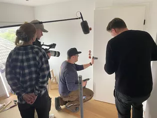 Videodreh Gewinnaktion mit die.tischlerin Die Abbildung zeigt wie ein Tischler mit der Bohrschablone Löcher in die Türe bohrt.