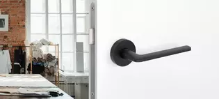 L'illustration montre la poignée de porte Remote de Griffwerk en Noir graphite dans une pièce d'habitation.