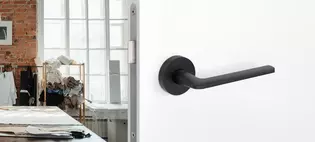 The picture shows the Griffwerk door handle Remote in graphite black in a living room.