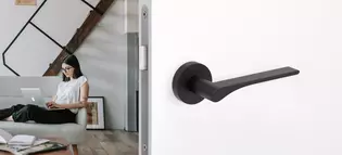 L'illustration montre la poignée de porte LEAF LIGHT de Griffwerk en noir graphite dans une pièce d'habitation.
