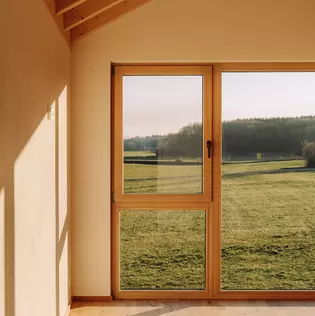 The illustration shows the window of a new living room in which the AVUS window handle in cashmere grey is installed.