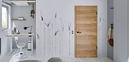 La imagen muestra una habitación juvenil con Puerta de madera y Manillas de puerta LUCIA negras con tecnología de cierre smart2lock.