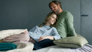 smart2lock - El clic hacia una mayor relajación Un matrimonio se acurruca en la cama y disfruta de la tranquilidad. Al fondo se ve la puerta cerrada con smart2lock, señalando: Ahora es el momento de relajarse. Tenemos paz y tranquilidad.