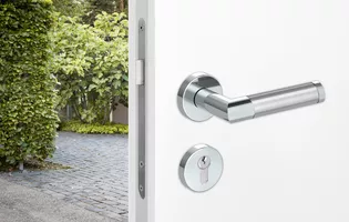 The illustration shows an entrance door with combination security fitting. On the outside a security fitting is mounted, on the inside of the interior door it is combined with a combination inner rose set and the GRIFFWERK handle Loredana.