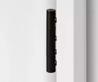 Paumelle pour porte en bois en 3 pièces en finition Noir graphite, représentée dans un cadre de porte en bois blanc