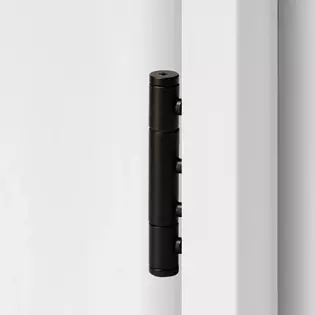 3-part wooden door hinge in the surface graphite black, shown in a white wooden door frame