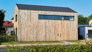 L'image montre l'extérieur de la maison vv avec des façades en mélèze naturel.