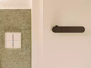 La imagen muestra las Manillas de puerta AVUS ONE en Gris cachemira en el cuarto de baño.