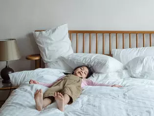 The illustration shows a child lying on a bed and relaxing.