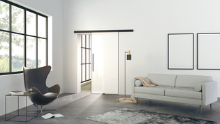 Die Abbildung zeigt ein modernes Wohnzimmer mit der Planeo Air Glasschiebetür von Griffwerk an einer Wand.