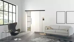 The picture shows a modern living room with the Planeo Air sliding door by Griffwerk on a wall.