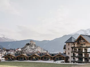 The picture shows the hotel Vaya Ladis located in the mountains in a beautiful wooden hut style. 