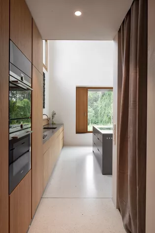 Le monolithe de cuisine en Corian d'un noir velouté correspond aux lourds rideaux gris clair en tissu doux. Les poignées de porte MINIMAL MODERN en Gris satiné s'intègrent parfaitement au concept.