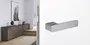 The picture shows the R8 One door handle by Griffwerk on a white door with a hallway in the background.
