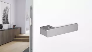 Abbildung R8 One Türgriff von Griffwerk an weißer Tür Die Abbildung zeigt den R8 One Türgriff von Griffwerk an einer weißen Tür mit einem Flur im Hintergrund.